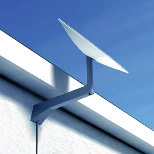 Starlink long wall mount fixed under a roof eave, holding the dish clear of the roofline against a blue sky.